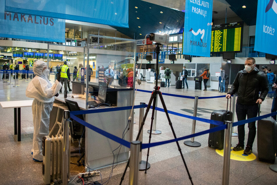 Ein Flughafenmitarbeiter kontrolliert die Temperatur der Passagiere auf dem Internationalen Flughafen Vilnius.