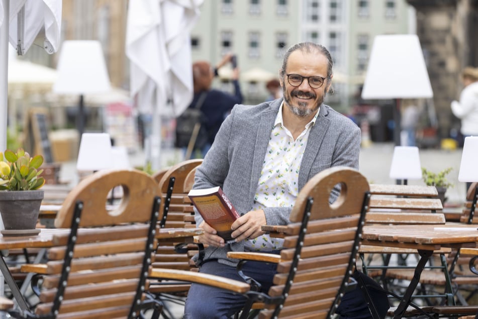 Frank Goldammer (50) mit seinem neuen Buch in den Händen - vormittags im Sitzmobiliar des Palais Sommers auf dem Dresdner Neumarkt.