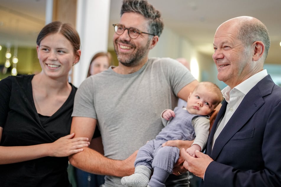 Bundeskanzler Olaf Scholz (65, SPD) posiert im Wahllokal mit einer Familie samt Baby.