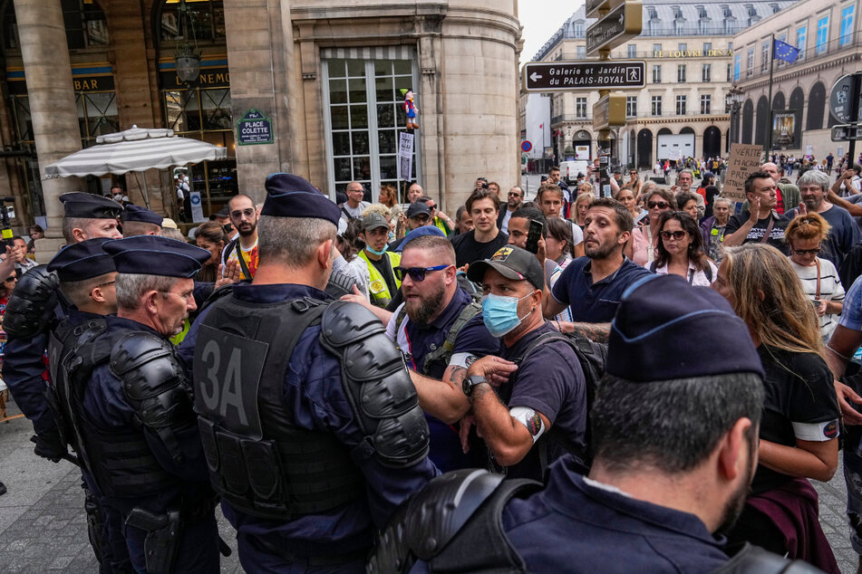 Paris: Menschen stehen bei einem Protest gegen den Gesundheitspass Polizisten gegenüber.
