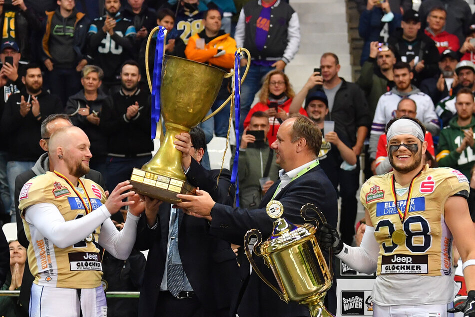 Dresdens OB Dirk Hilbert (2.v.l.) übergibt den Pott an Monarchs Backup-Quarterback Eric Seidel. Der Wanderpokal wird nun (mindestens) ein Jahr in Dresden stehen. Die kleine Trophäe, die Florian Zur Nieden in der Hand hat, verbleibt für immer im Besitz der Königlichen.