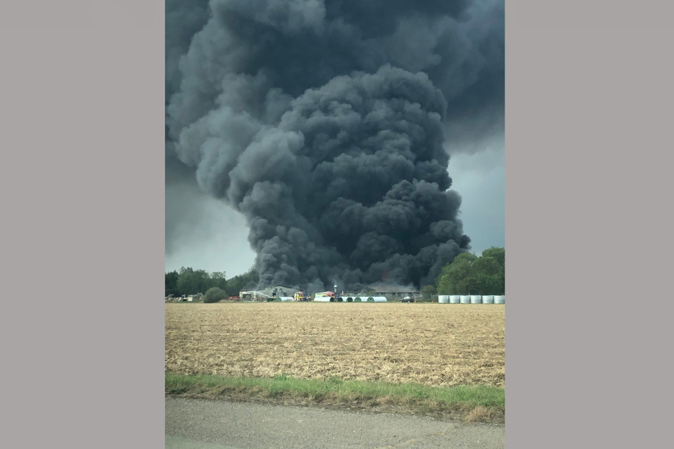 Eine schwarze Rauchsäule steigt über einer Industrieanlage in der Nähe des Parham Airfield in Suffolk in den Himmel. Feuerwehrleute kämpfen noch immer gegen das Feuer in der Anlage.