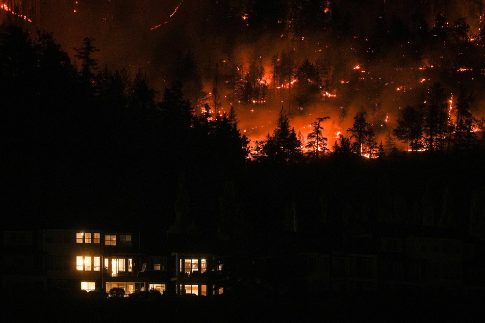Das McDougall Creek-Wildfeuer brennt am Freitag an einem Berghang oberhalb eines Hauses in West Kelowna.