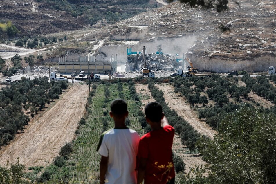 Palestinian children watch as Israeli forces oversee the demolition of a building containing shops and homes in Anzah, south of Jenin in the Israeli-occupied West Bank, on July 27, 2026.