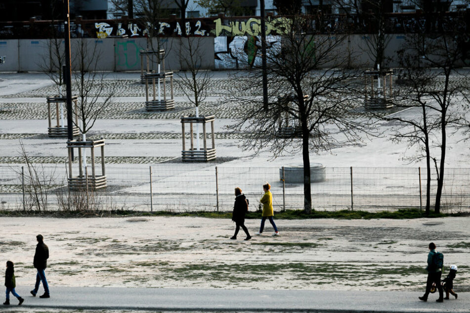 Menschen gehen im Mauerpark mit großem Abstand zueinander spazieren.