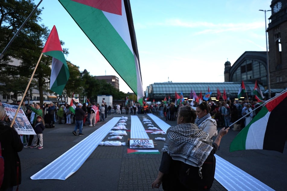 Teilnehmer halten während der propalästinensischen Demonstration Plaktae "Drei Jahre Genozid" hoch.