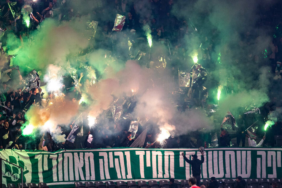 Die mitgereisten Anhänger von Maccabi Haifa brennen ein Pyro-Feuerwerk im Gästeblock ab.