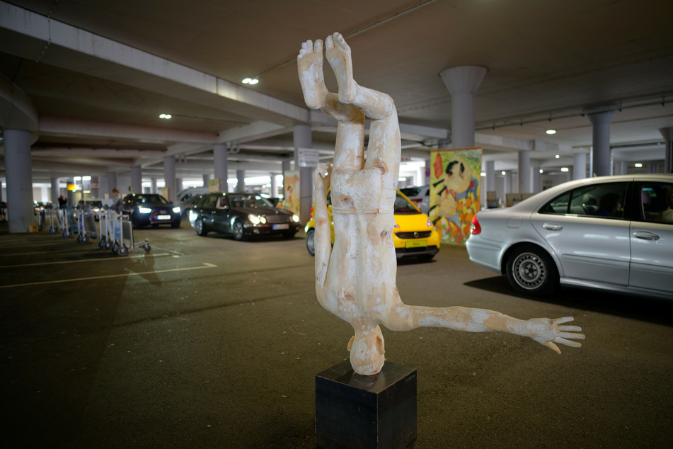 Ausstellungsbesucher fahren in Autos an der Skulptur des Künstlers Hubert Mussner vorbei, welche im Parkhaus P1 des Flughafens Köln-Bonn steht.