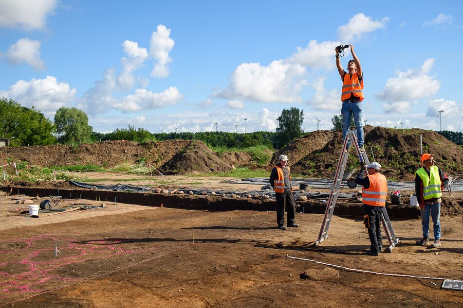 Archäologen vom Landesamt für Denkmalpflege und Archäologie Sachsen-Anhalt fotografieren die Grabungsfläche.
