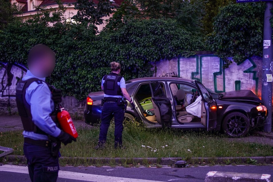 Polizisten untersuchen das zu Schrott gefahrene Auto.