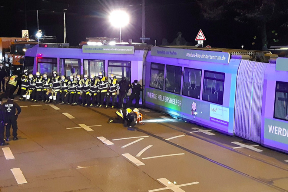 Einsatzkräfte der Feuerwehr schieben die Tram mit vereinten Kräften zurück auf die Schienen.