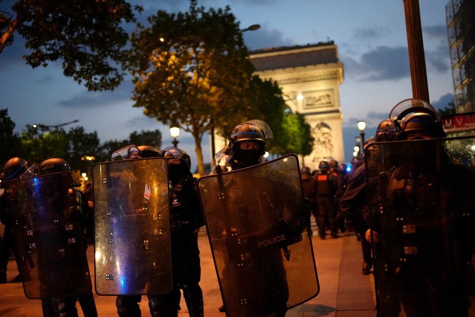 Polizisten patrouillieren vor dem Arc de Triomphe auf der Champs Élysées. Aufgrund der anhaltenden Unruhen in Frankreich waren in der Nacht zum Sonntag erneut 45.000 Polizisten im Einsatz sein.