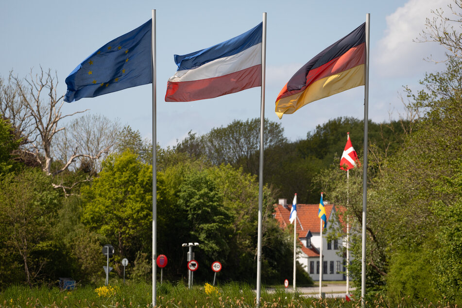 Die Flaggen von Europa (l-r), Schleswig-Holstein, Dänemark und Deutschland wehen am deutsch-dänischen Grenzübergang Kupfermühle/Krusa bei Flensburg.
