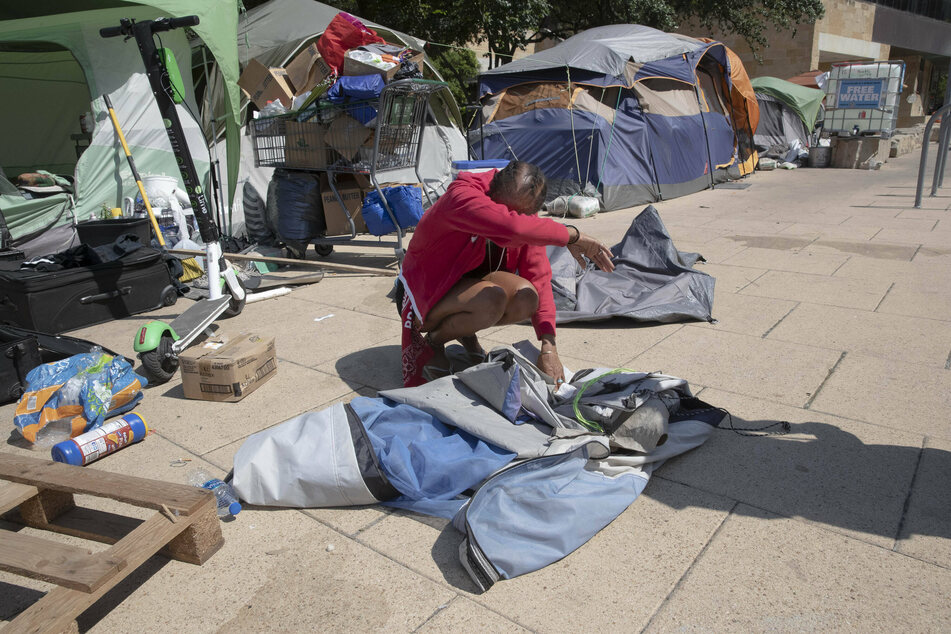 A woman waits outside a tent while city workers cleaned out a homeless protest camp on the north side of City Hall in Austin, Texas, on June 14, 2021.