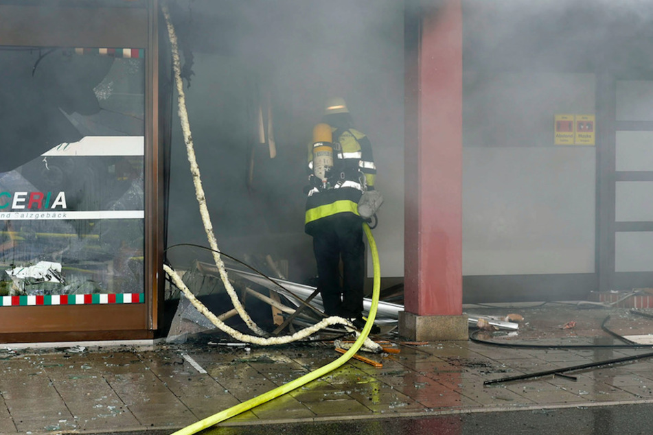 Ein Feuerwehrmann löscht den Brand in der Pizzeria.
