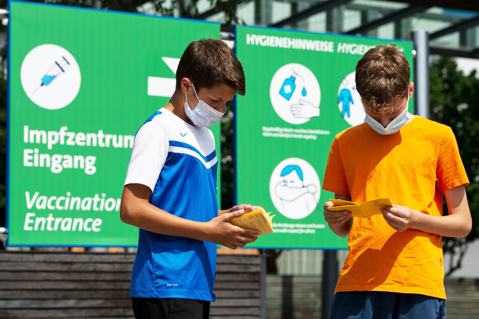 Die Geschwister Hugo (12) und Urs (13) blättern vor einem Impfzentrum in ihren Impfbüchern. In Sachsen dürfen sie sich nun gegen Corona immunisieren lassen.