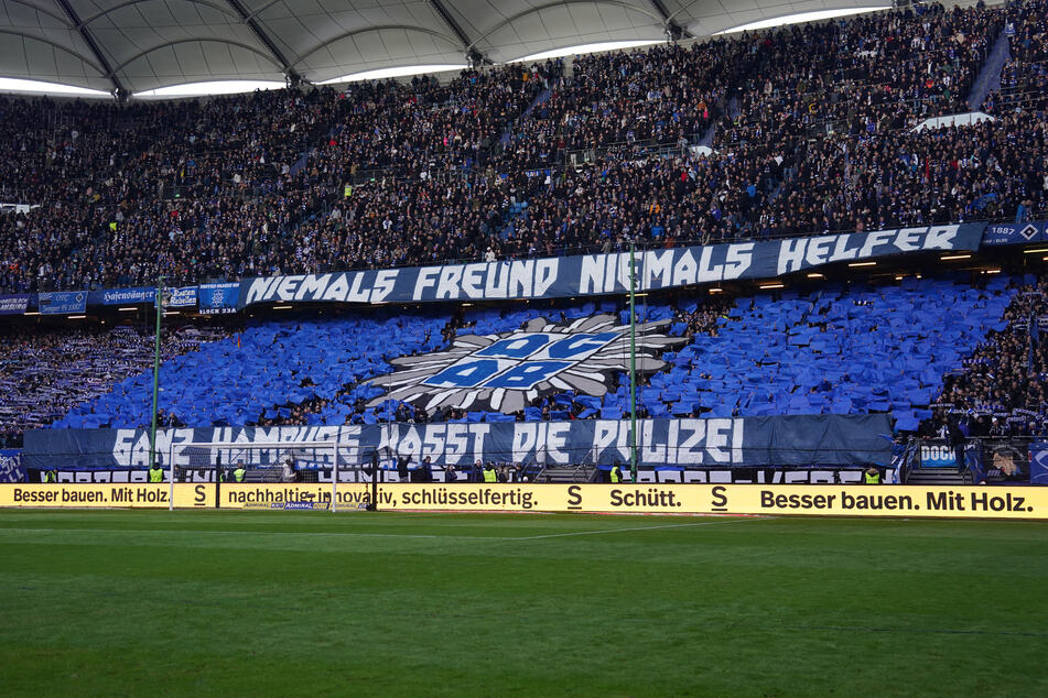 HSV-Fans halten Plakate mit der Aufschrift "Niemals Freund, niemals Helfer" und "Ganz Hamburg hasst die Polizei" hoch.