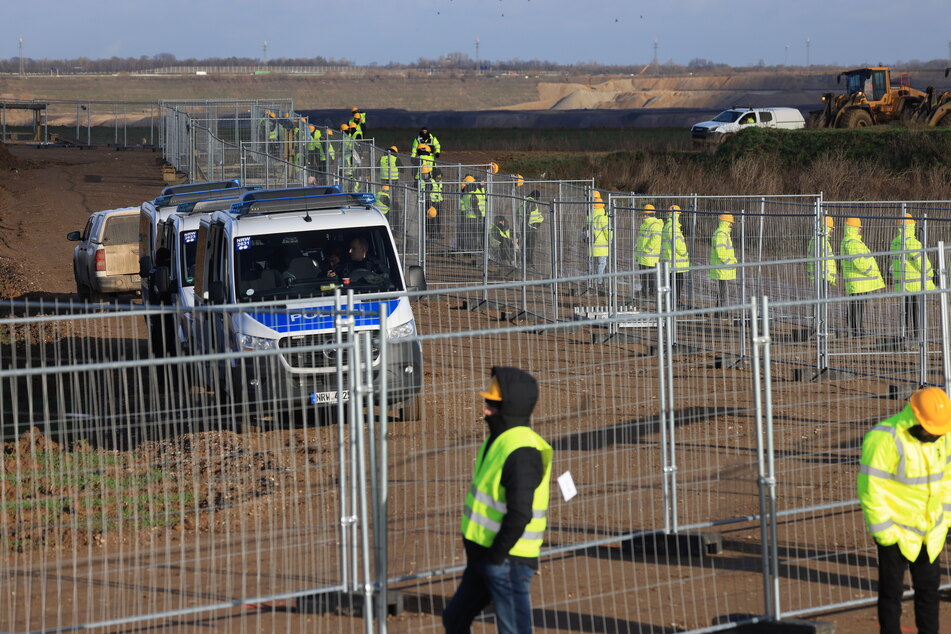 Mitarbeiter einer Werkschutzfirma sichern den neu errichteten Zaun.