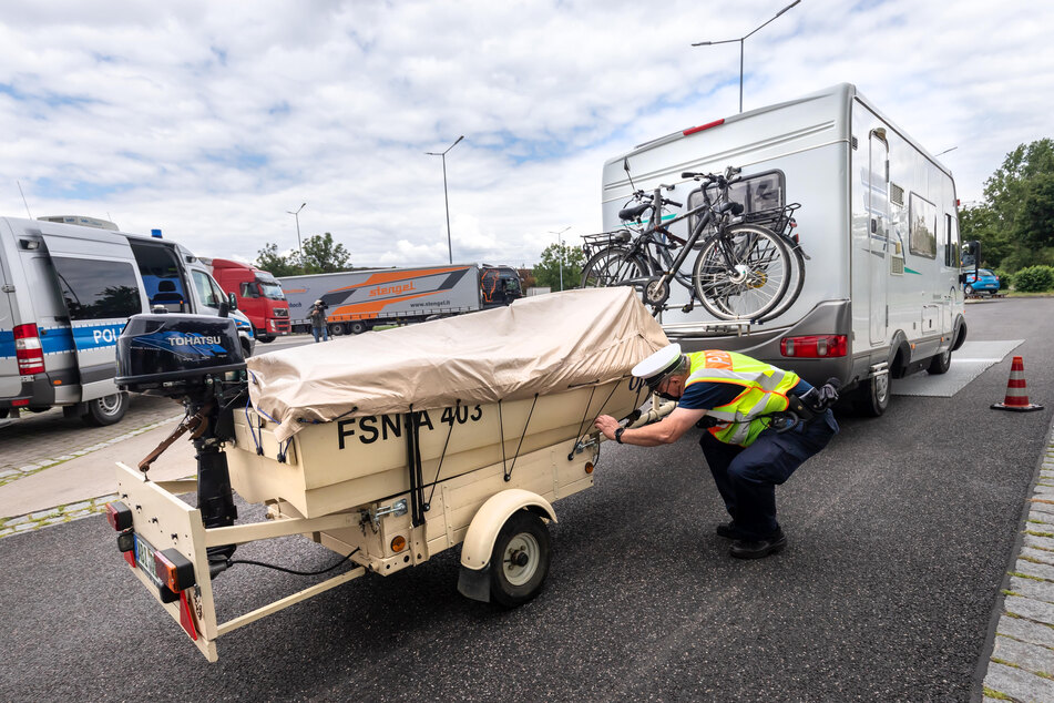 Wohnmobil mit Anhänger: Hier schaut sich ein Polizist ein Motorboot an.