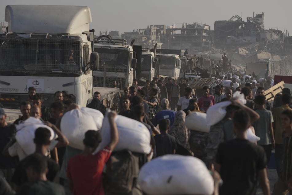Palästinenser tragen Mehlsäcke, die von einem humanitären Hilfskonvoi geliefert wurden, der Gaza-Stadt aus dem nördlichen Gazastreifen erreichte.