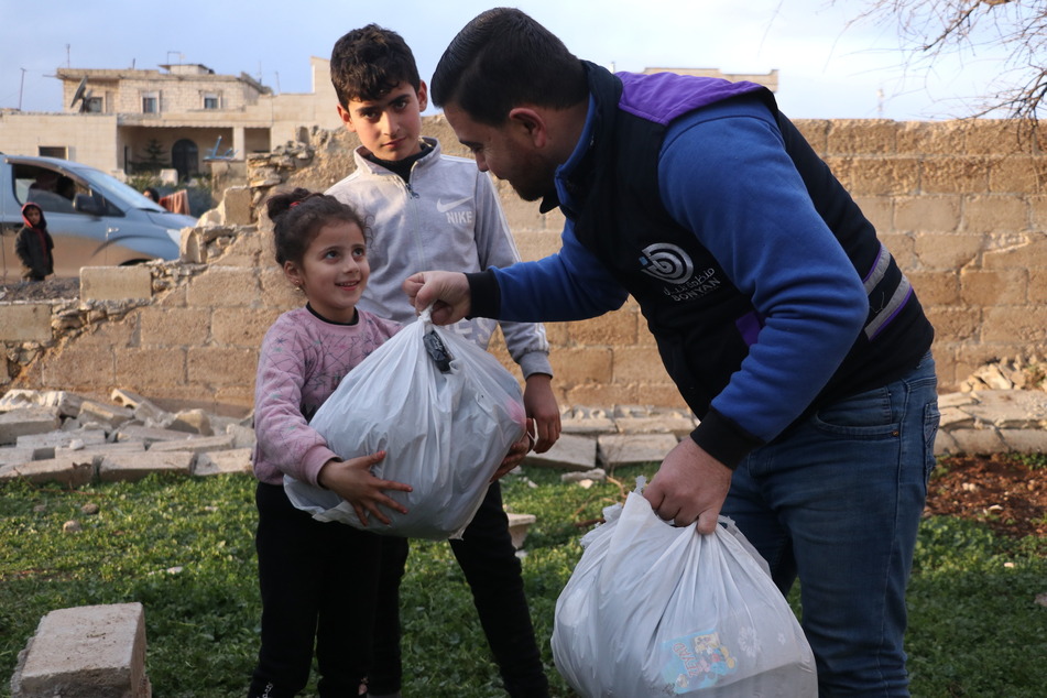 Ein Mitarbeiter der Partnerorganisation "Bonyan" verteilt Hilfspakete an syrische Kinder.