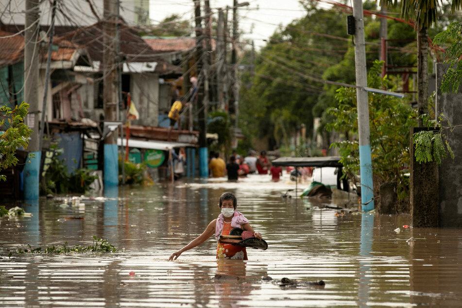 Residents wade through waist-deep flood waters after Super Typhoon Noru, in San Miguel, Bulacan province, Philippines.