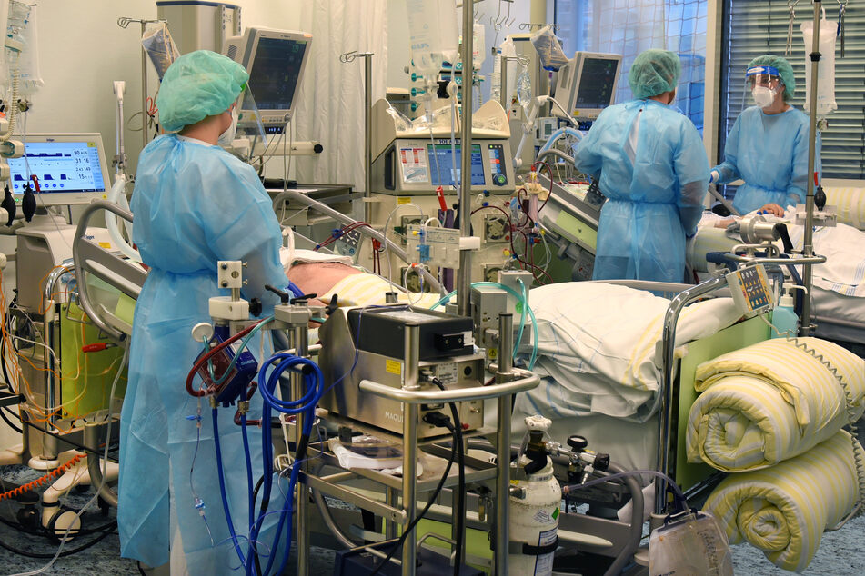 Auf der Covid-Station, einem Bereich der Operativen Intensivstation vom Universitätsklinikum Leipzig, stehen ein Arzt (2.v.r.) und zwei Schwestern an Betten von Patienten.