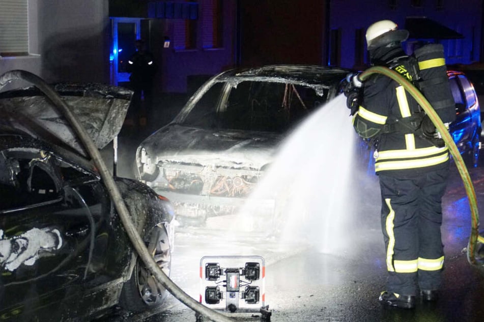 Feuerwehrmann löscht eines der brennenden Autos.