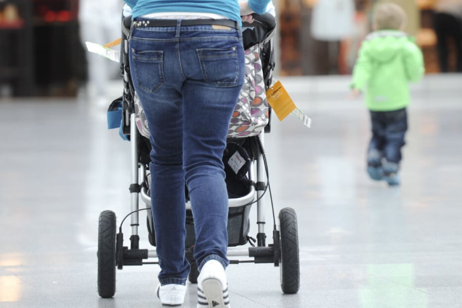 Eine Mutter geht mit einem Kinderwagen einen Weg entlang. (Symbolbild)