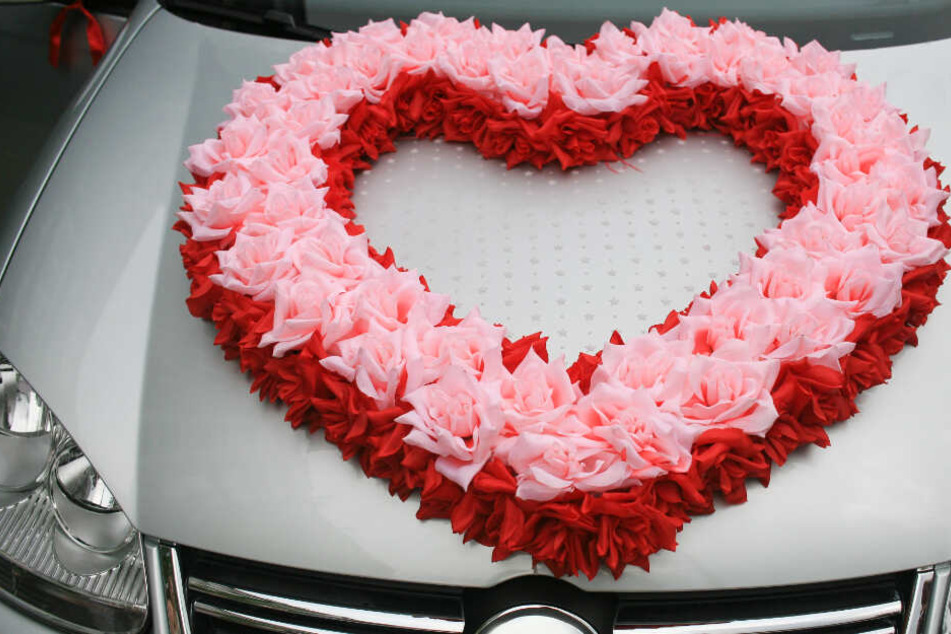 Auf der Motorhaube eines Autos ist ein Herz aus Blumen gelegt. (Symbolbild)