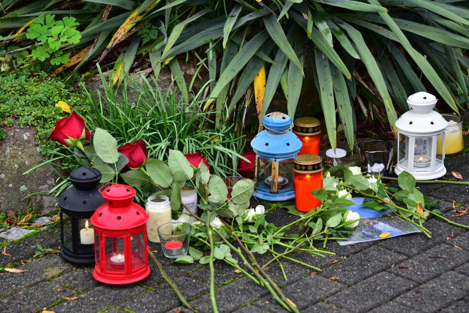 Blumen und Kerzen wurden vor dem Wohnhaus abgelegt, in dem Vater, Mutter und Tochter starben.