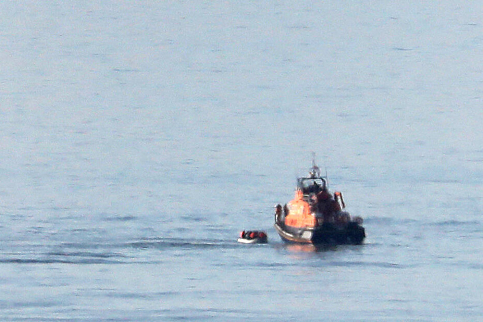 Ein Rettungsboot (r) nähert sich einem kleinen Boot, von dem angenommen wird, dass es Migranten befördert.