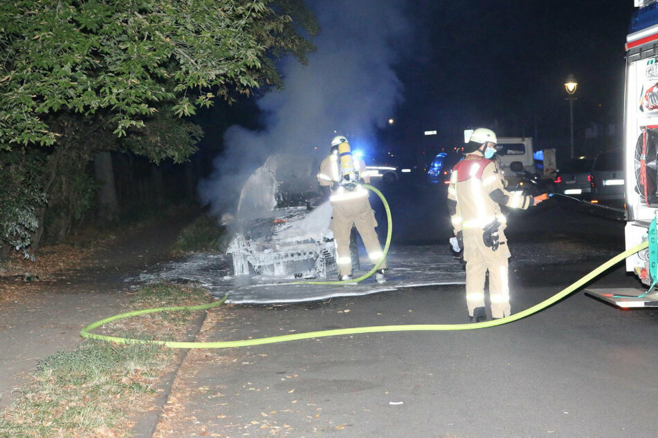 Einsatzkräfte der Feuerwehr löschen ein Auto in Berlin-Neukölln.