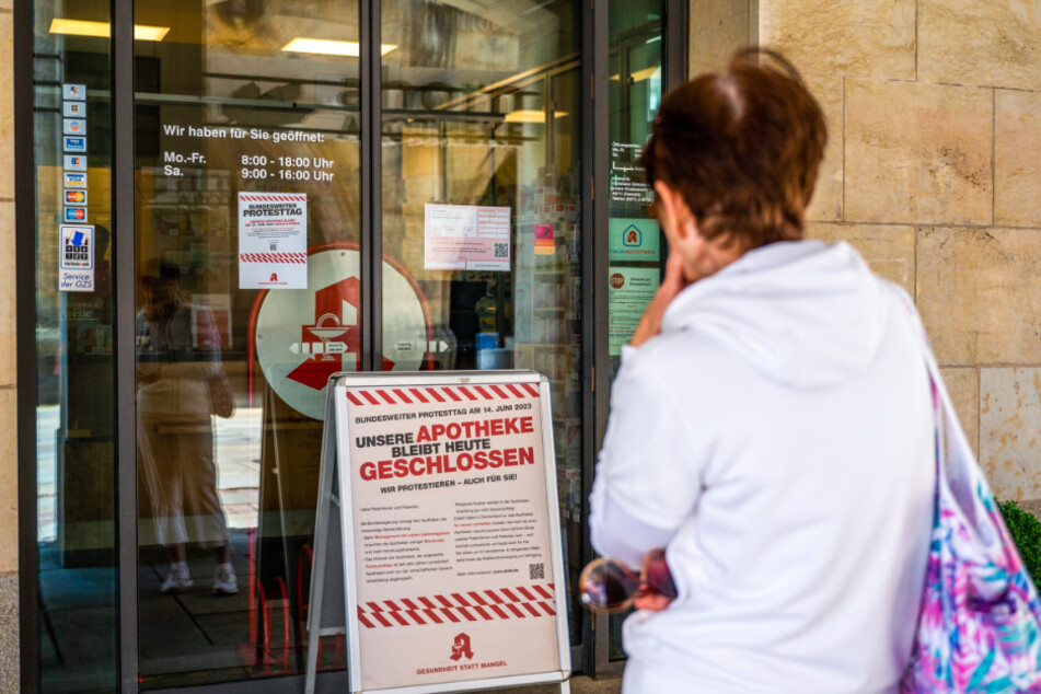 Eine verhinderte Kundin liest ein Protestplakat vor der Ahorn-Apotheke.