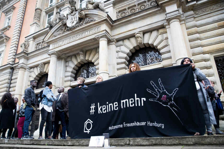 Menschen stehen bei einer Mahnwache für die getötete Frau vor dem Strafjustizgebäude.