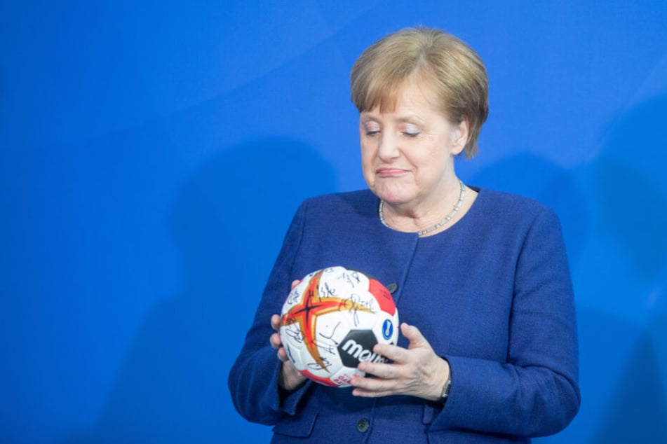 Bundeskanzlerin Angela Merkel schaut sich den unterschriebenen Handball der deutschen Nationalmannschaft an.