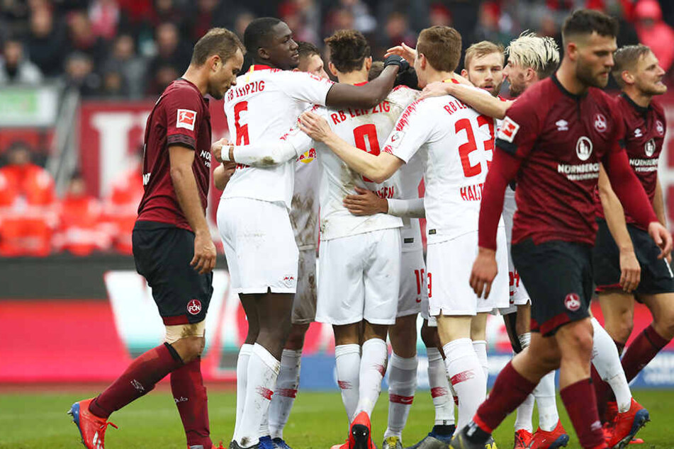 Die Spieler von RB Leipzig bejubeln das 1:0, während Nürnbergs Kicker niedergeschlagen zu Boden gucken.