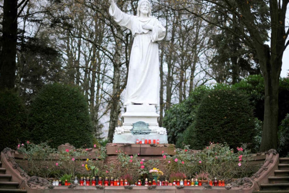 Vor einer Christusstatue auf dem Friedhof Ohlsdorf stehen zahlreiche Kerzen. Der Besuch mit dem Auto soll bald Eintritt kosten.