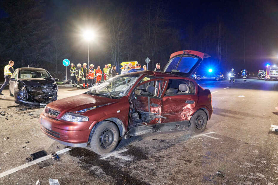 Helfer stehen neben den zwei beschädigten Autos auf einer Kreuzung.
