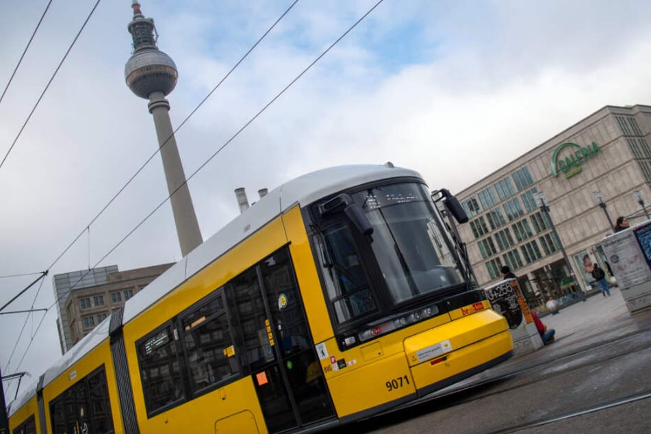 Eine Straßenbahn der Berliner Verkehrsbetriebe (BVG) fährt vor dem Fernsehturm über den Alexanderplatz.