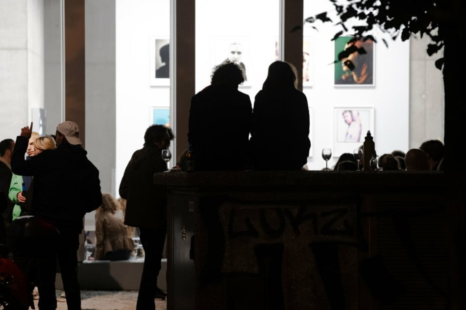 Menschen sitzen am Abend vor einer Galerie in Berlin.