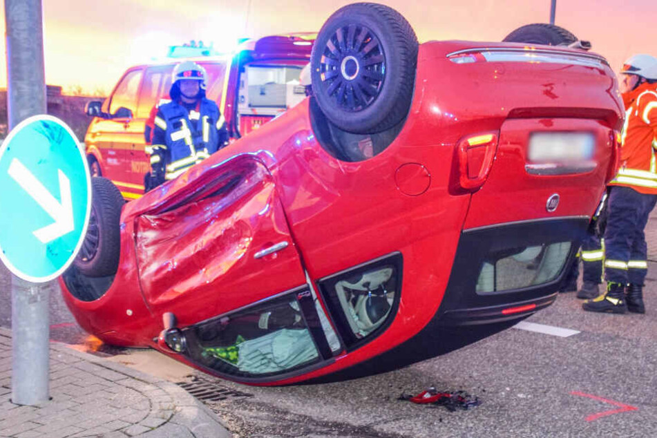 Ein Auto liegt auf dem Dach auf der Straße.