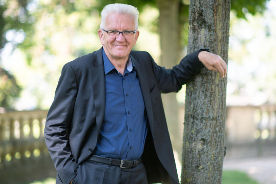 Ministerpräsident Winfried Kretschmann lehnt an einem Baum.