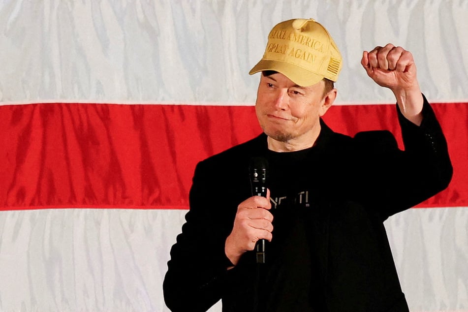 Tesla CEO and X owner Elon Musk, who supports Republican presidential nominee Donald Trump, raises his fist as he speaks about voting during an America PAC Town Hall in Folsom, Pennsylvania.