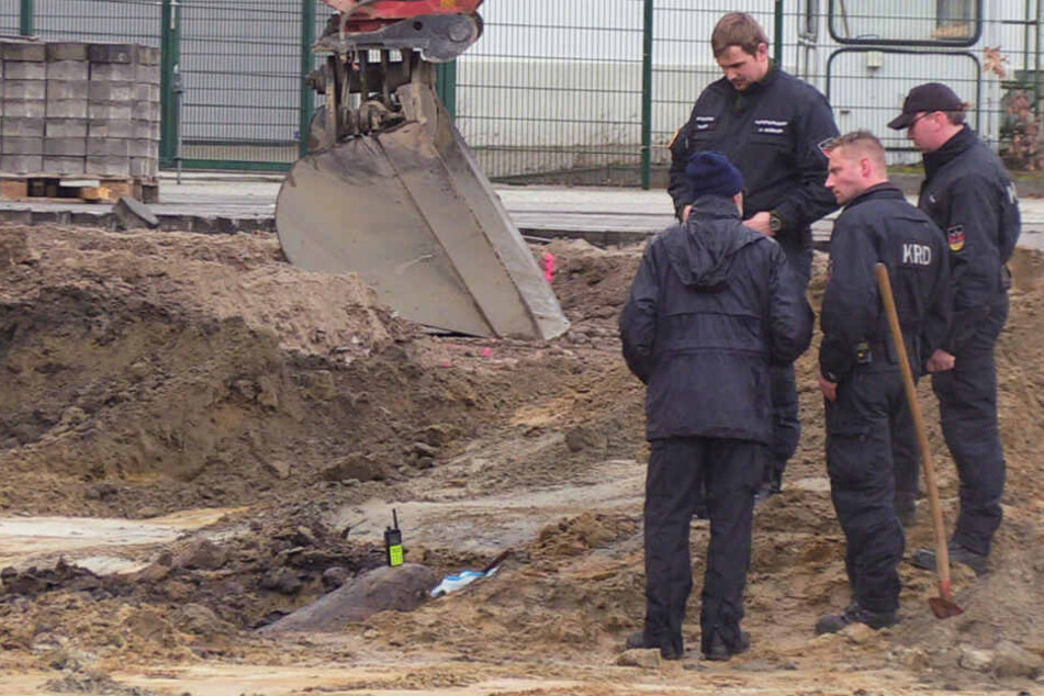Einsatzkräfte des Kampfmittelräumdienstes stehen an der Fundstelle.
