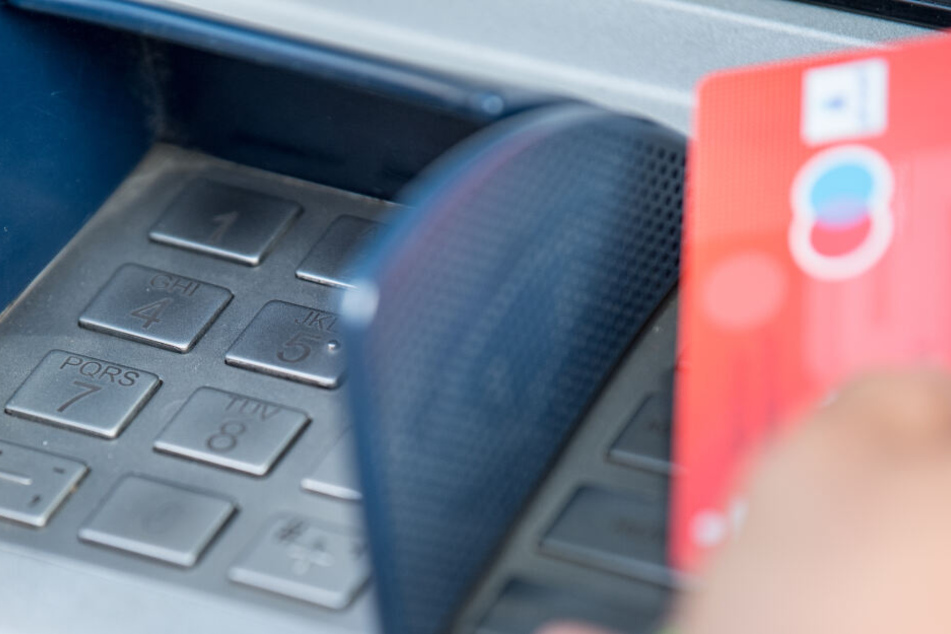 Eine Bankkundin hebt mit ihrer Girokarte Bargeld von einem Geldautomaten ab.
