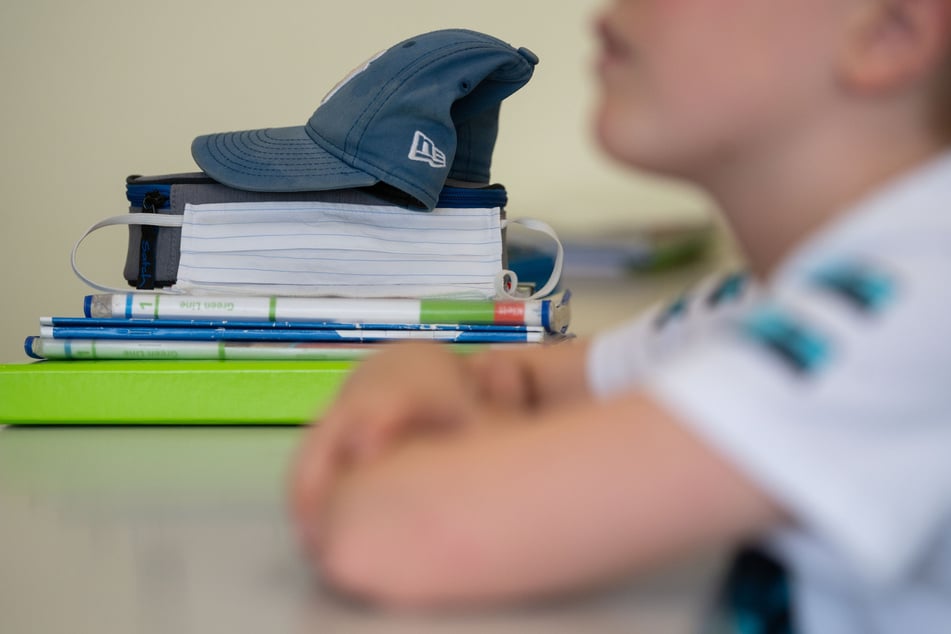 Eine Mund-Nasen-Bedeckung lehnt während einer Unterrichtsstunde einer fünften Klasse des Friedrich-Schiller Gymnasiums an Büchern.