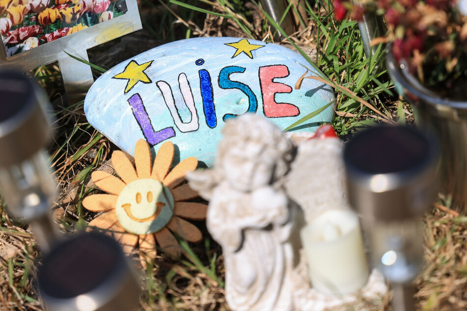 Ein Stein mit dem aufgemaltem Namen "Luise" liegt am Waldrand an der Stelle, an der das zwölfjährige Mädchen tot gefunden wurde.