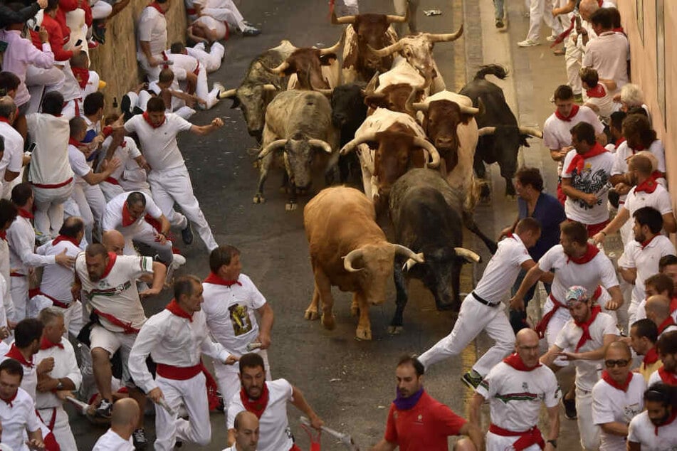 Mehrere Männer laufen bei der traditionellen Stierhatz durch die Straßen.
