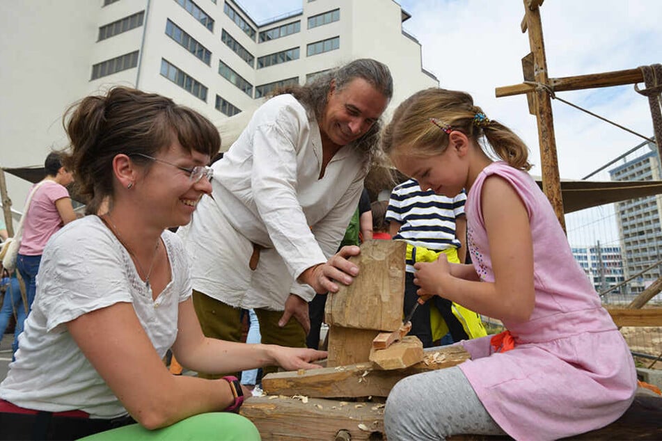 Romy Wenke (37, v.l.) und Klara (8) schnitzen Löffel bei Carsten Scholz (61). Tony Meier (11) als Polizist auf dem Behördenfest.